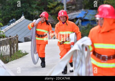 (201120) -- RONGSHUI, 20. November 2020 (Xinhua) -- Freiwillige bringen am 19. November 2020 unter Anleitung professioneller Feuerwehrleute Rohre nach einer Feuerübung in das Dorf Wuying, ein abgelegenes Dorf, das von der ethnischen Gruppe Miao an der Grenze zwischen der Autonomen Region Guangxi Zhuang im Süden Chinas und der Provinz Guizhou im Südwesten Chinas bewohnt wird. Da die Häuser mit dem lokalen Baustil im Dorf von einer bewaldeten Struktur unterstützt werden, wird ein Team von weiblichen Freiwilligen Feuerwehrleuten gebildet, um ihr Dorf zu schützen, da die meisten jungen und mittleren Alters Männer als Migranten ausziehen. (Xinhua/Huang Xiaobang Stockfoto