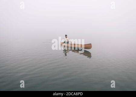 Hipster Mann Paddeln Kanu auf dem nebligen See Stockfoto