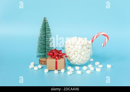 Geschenkbox, weihnachtsbaum und Tasse Marshmallows mit rotem Lollipop Stock auf blauem Hintergrund. Frohe Weihnachten oder Happy New Year Konzept. Vorlage für yo Stockfoto