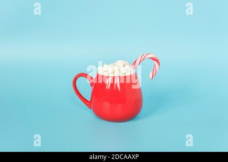 Große rote Tasse Marshmallows mit Lollipop Stock auf blauem Hintergrund. Frohe Weihnachten oder Happy New Year Konzept. Minimaler Stil, Draufsicht, flache Lay-Anordnung, Kopieren Stockfoto