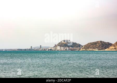 Gesamtansicht von Alicante Stadt vom blauen Mittelmeer mit dem Hafen, Gebäude und der Burg Stockfoto