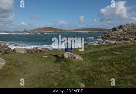 Weibliche Walker sitzt auf einem Granite Rock bewundern den Blick über Hell Bay auf der Insel Bryher in den Isles of Scilly, England, Großbritannien Stockfoto