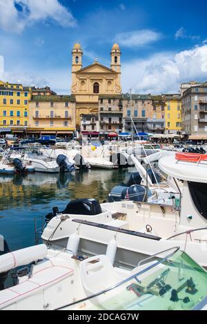 Blick auf die église Saint Jean-Baptiste in Bastia vom vieux Hafen mit einigen Booten, die im Sommer im Hafen ruhen Stockfoto