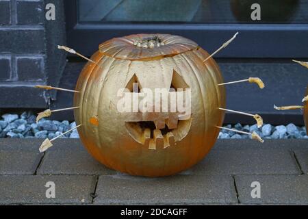 Hausgemachter Halloween Kürbis mit Goldfarbe bemalt und eingebaut Vorderseite der Tür Stockfoto