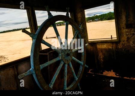 Ein großes Holzlenkrad ist auf der Kapitänsbrücke eines alten Goldbagges zu sehen, der im Fluss Atrato in Quibdó, Kolumbien, verankert ist. Stockfoto