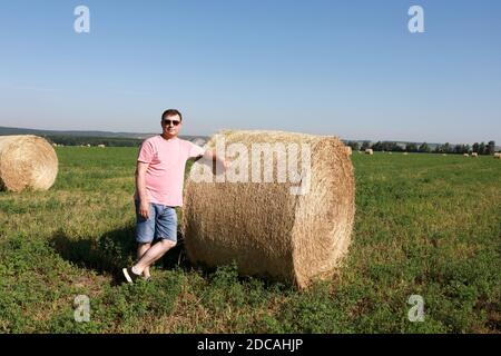 Mann mit Strohballen auf dem Feld im Sommer Stockfoto