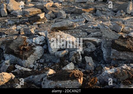 Zerbrochene Asphaltstücke auf einer Baustelle. Recycling und Wiederverwendung zerkleinerten Betonschutt, Asphalt, Baumaterial, Blöcke. Zerstoßenes Betonrückseite Stockfoto