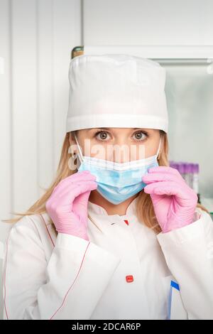 Die Krankenschwester oder Ärztin trägt Schutzhandschuhe, die medizinische Hilfe anziehen Gesichtsmaske im Labor Stockfoto