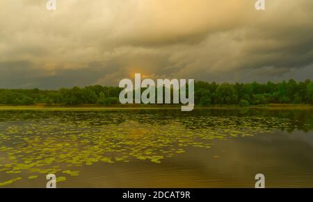 Landschaft von einem See Pogoria II kurz nach dem Sturm an einem Frühlingstag. Schwere Wolken über dem Horizont mit Sonnenlicht in der Mitte. Stockfoto