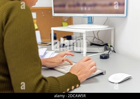 ZAGREB, KROATIEN - Nov 06, 2020: Ckose-up von Frau, die am Computer im Büro arbeitet und auf der Tastatur tippt. Stockfoto