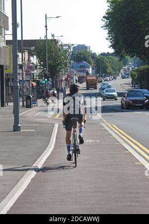 London, Großbritannien. Ein Radfahrer nutzt die neue abgetrennte Radstraße entlang der belebten Lea Bridge Road, die Teil des Mini-Holland-Plans von Waltham Forest für sicherere Straßen ist. Stockfoto