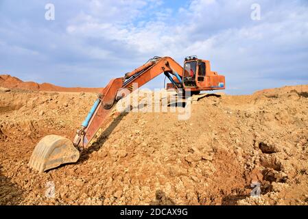 Bagger arbeiten auf Erdbewegung im Tagebau. Bagger gräbt Kies im Steinbruch. Baumaschinen für Aushub, Verladung, Heben und Heulin Stockfoto
