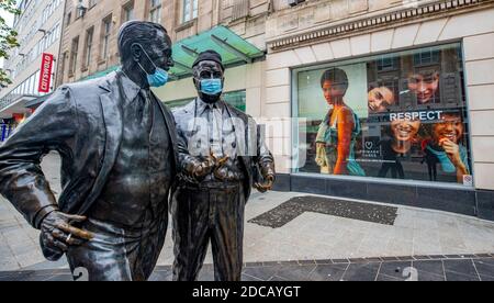Die Bronzestatuen von John und Cecil Moores, den Gründern der Littlewoods Company in Liverpool, die Gesichtsmasken aufgesetzt haben, während England eine vierwöchige nationale Sperre fortsetzt, um die Ausbreitung des Coronavirus einzudämmen. Stockfoto