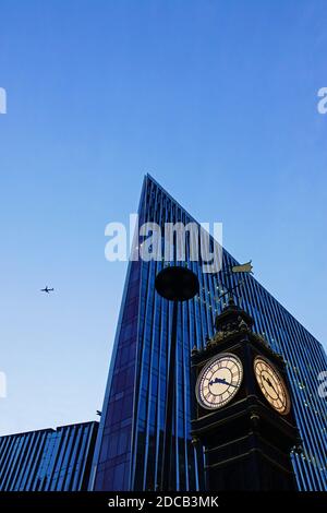 Sauberer Nachmittag in London mit einer schönen Perspektive auf die Little Ben Uhr, einem modernen Wolkenkratzer und einem Flugzeug Stockfoto