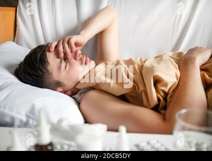 Schläfriger und kranker junger Mann im Bett im Zu Hause Stockfoto
