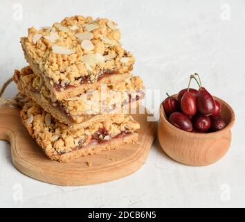 Stapel von gebackenen Krümel Pie mit Fruchtfüllung und bestreut Mit geriebenen Mandeln auf einem Holzbrett Stockfoto