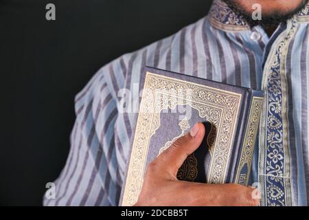 Muslimischer Mann Hand hält Koran isoliert auf schwarz Stockfoto