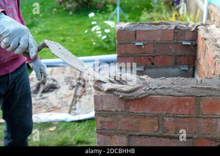 Nahaufnahme von Maurerziegeln mit Maurerkelle und Mörtel Gebäude einen Grill im Freien im Sommer Stockfoto