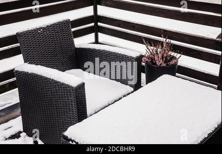 Nahaufnahme von verschneiten synthetischen Kunststoff Rattan und Glas Gartenmöbel an kalten Wintertag. Gartenmöbelpflege-Konzept. Stockfoto