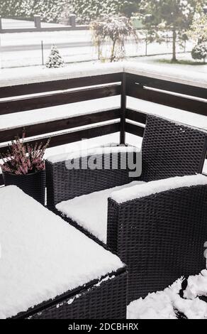 Nahaufnahme von verschneiten synthetischen Kunststoff Rattan und Glas Gartenmöbel an kalten Wintertag. Gartenmöbelpflege-Konzept. Stockfoto