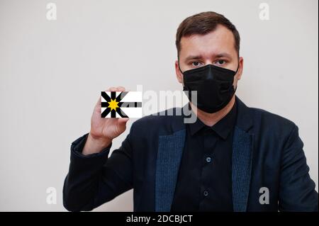 Mann tragen schwarz formell und schützen Gesichtsmaske, halten Sutherland Flagge Karte isoliert auf weißem Hintergrund. Vereinigtes Königreich Grafschaften Schottland Coronavirus C Stockfoto