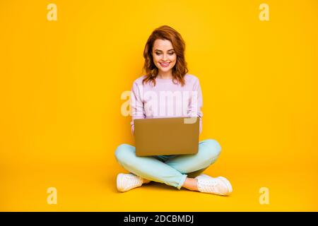 In voller Größe Foto von positiven fröhlichen Frau sitzen Beine gekreuzt Verwenden Sie Computer Nachrichten lesen Kommunizieren Sie online mit Kollegen Familienkleidung blaugrün-Jumper isoliert Stockfoto