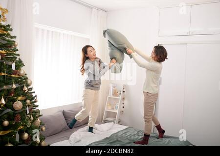 Zwei Freundinnen genießen Kissenschlacht springen auf Bett Stockfoto