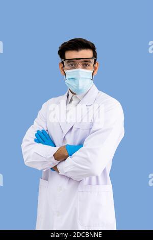 Porträt von zuversichtlich männlichen Nahost-arabischen Forscher Wissenschaftler medizinische Arzt trägt OP-Maske und Schutzbrille stehen über die Arme Ist Stockfoto