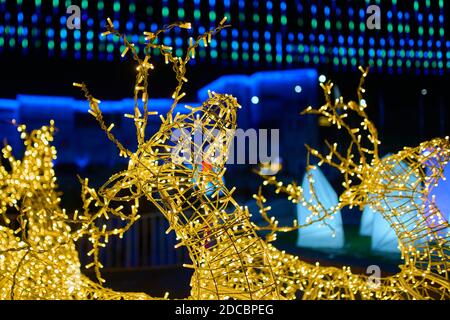 Funkelnde Figur des Weihnachtshirns. Goldene Weihnachtsgirlande. Beleuchtung bei Nacht. Winterfest. Feiertagslichter in Form von Hirschen auf der Straße. Heiligabend. Konzept des neuen Jahres. Stockfoto