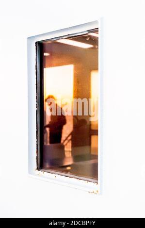 Die Spiegelung des Meeres und ein Passagier bei der Sonne steigen im Fenster einer Fähre Überfahrt von Nizza Frankreich nach Korsika. Stockfoto