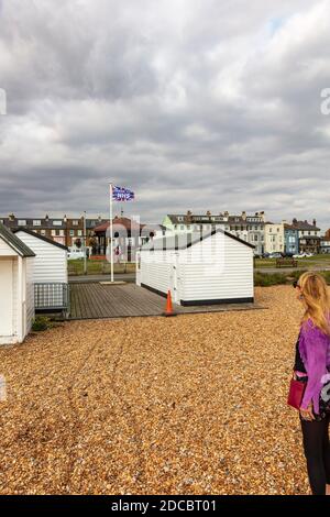 Eine Frau schaut auf eine Danke NHS Flagge, die zwischen Strandhütten fliegt, am Strand bei Deal, während der Zwangsbeschränkungen, Kent, Großbritannien Stockfoto