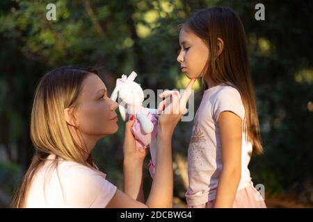 Junge Mutter umarmt ihre weinende kleine Tochter. Traurige Tochter in den Armen ihrer Mutter. Stockfoto