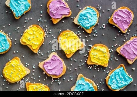 Lustiges geröstetes Brot mit farbigem Käseaufstrich. Overhead-Ansicht Stockfoto