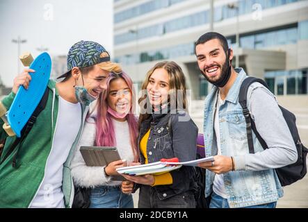 Glückliche junge Menschen treffen sich im Freien und tragen Gesichtsmasken während covid-19 Pandemie - Gruppe von fröhlichen Jugendlichen Spaß haben, Konzepte über Teenager, Stockfoto