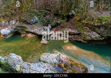 Herbstlandschaft mit Bergbach, der zwischen moosigen Steinen fließt Stockfoto