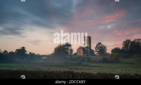 Morgenhimmel über der Swanton Morley Kirche an einem nebligen Herbstmorgen. Stockfoto