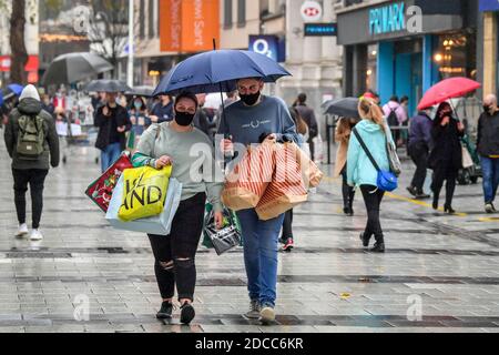 Mit Taschen beladene Käufer tragen Brollys im Zentrum von Cardiff, wo Geschäfte geöffnet sind und die Menschen in Zahlen sind und die Vorteile des Kaufens von unwesentlichen Gegenständen im Vorfeld von Weihnachten nutzen. Die Beschränkungen in ganz Wales wurden nach einer zweiwöchigen „Feuerpause“-Sperre gelockert. Stockfoto