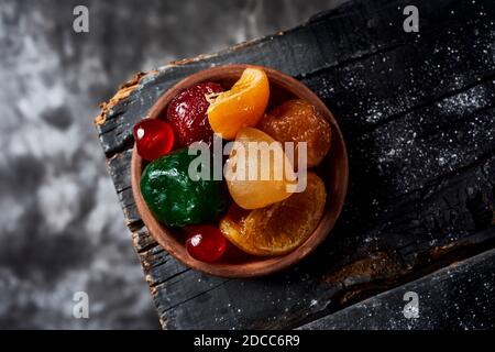 Blick aus der Vogelperspektive auf einige appetitliche spanische kandierte Früchte, wie Orange, Birne, Pflaume oder Maraschino Kirschen, in der Regel zu weihnachten gegessen, auf einem rustikalen Stockfoto