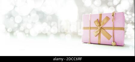 Rosa Geschenkbox mit Goldband und goldenen Dekorationen. Bokeh-Hintergrund. Seitenansicht. Speicherplatz kopieren. Stockfoto