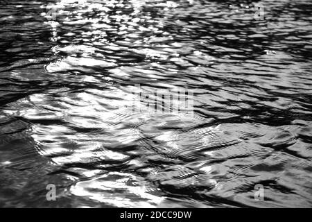 Dunkel schimmerndes Wasser plätschert vom See. Stockfoto