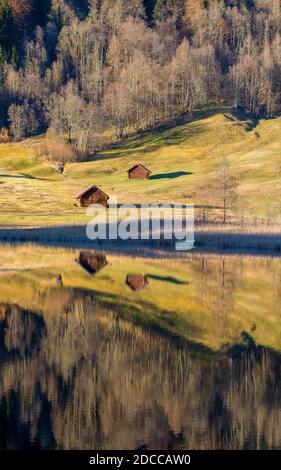 Schöne Holzhütten umgeben von Herbstbäumen in Berg reflektiert see Stockfoto