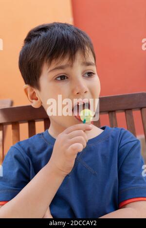 Happy Childhood Konzept. Schneiden Sie kleinen Jungen essen Lollipop Süßigkeiten und Spaß im Freien Stockfoto