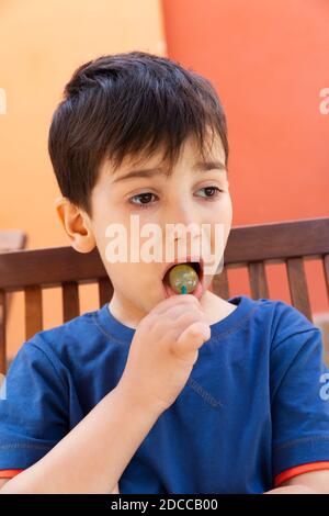 Happy Childhood Konzept. Schneiden Sie kleinen Jungen essen Lollipop Süßigkeiten und Spaß im Freien Stockfoto