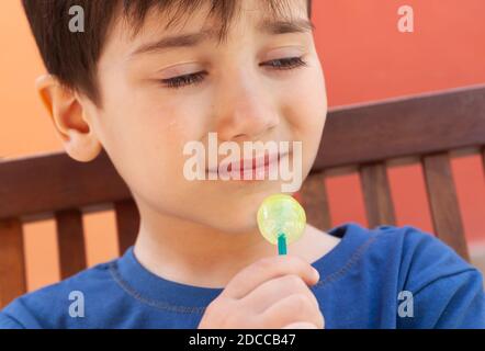 Happy Childhood Konzept. Schneiden Sie kleinen Jungen essen Lollipop Süßigkeiten und Spaß im Freien Stockfoto