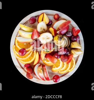 Obst schneiden auf einem Teller. Apelsygs, Trauben, Äpfel und Erdbeeren. Stockfoto