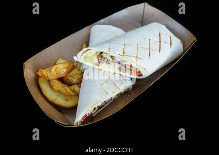 Pita shawarma ist gefüllt mit Fleischgemüse, Gewürzen und Sauce. Mit pommes frites. In einem Pappteller. Stockfoto
