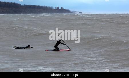 Paddle Board Surfen in extremen Sturmbedingungen mit hohen Wellen, Port Stanley Ontario Kanada am Nordufer des Eriesees. Stockfoto
