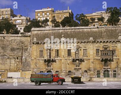 Ein alter LKW und Lagerhäuser unter der Stadtmauer am Wasser, Valletta, Malta Stockfoto