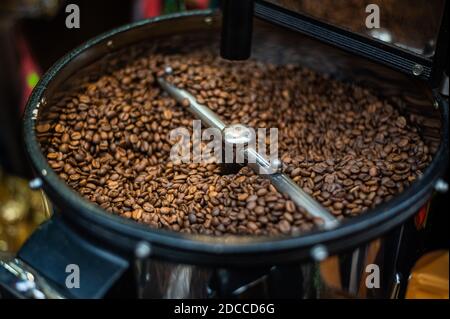 Nahaufnahme des Röstens von frisch gebratenen Kaffeebohnen. Die verarbeiteten Kaffeebohnen werden um eine Kühlplatte des Backofens herum gemischt Stockfoto