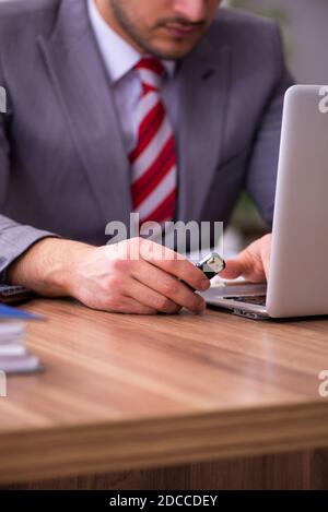 Männlicher Mitarbeiter, der Flash-Laufwerk in den Laptop einsteckt Stockfoto
